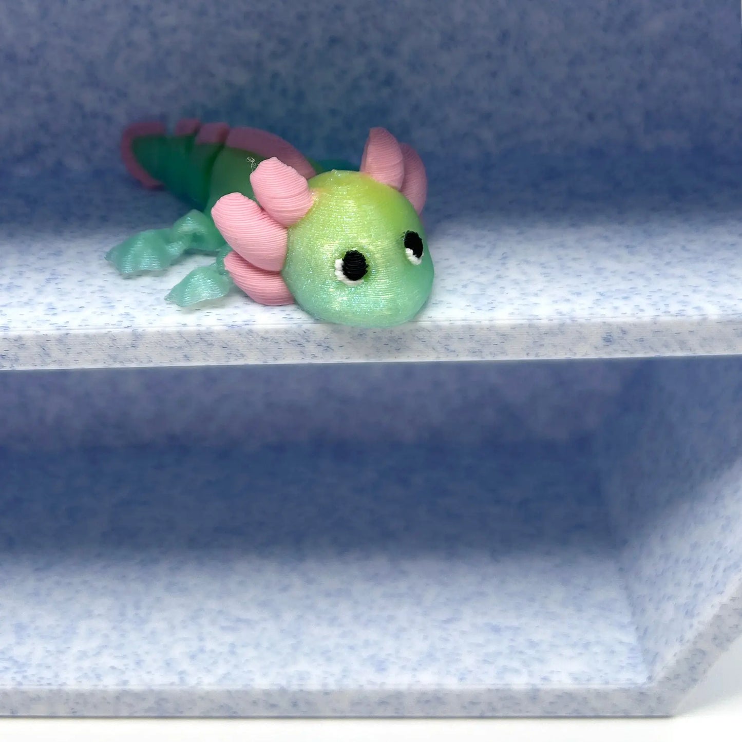 3D printed axolotl on a blue and white 3D printed shelf.